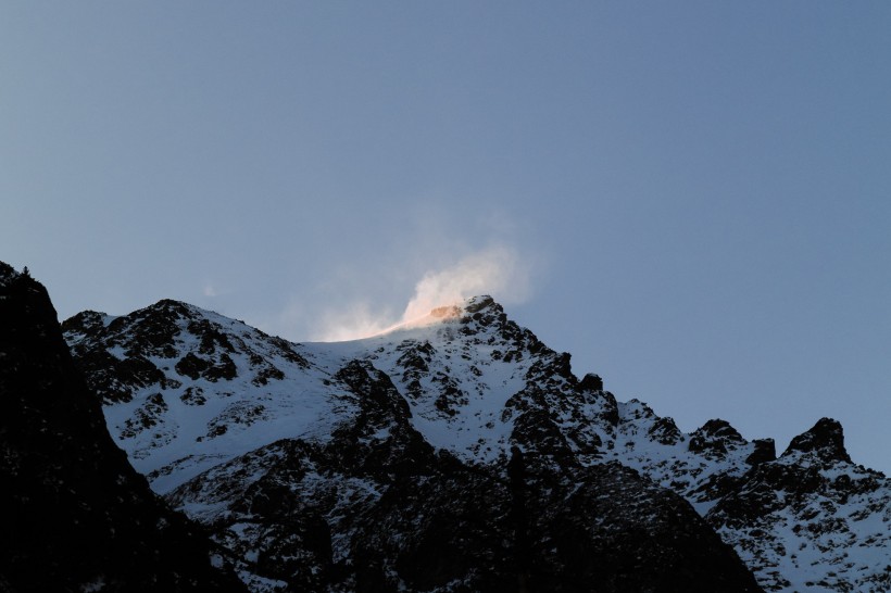 風中揚起白霧的雪山圖片