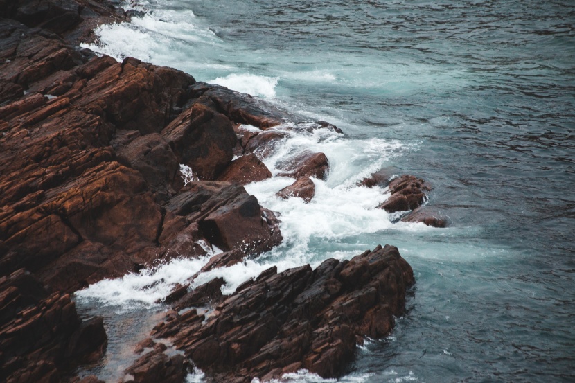 拍擊岸邊礁石的海浪圖片