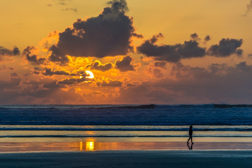 在海邊看日落的人圖片