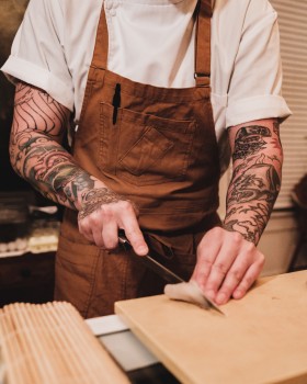 雙臂有紋身的準備做西餐的廚師圖片
