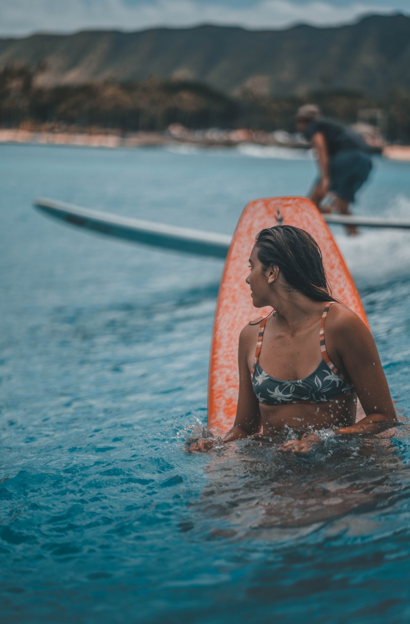 海邊抱着沖浪闆的女子圖片