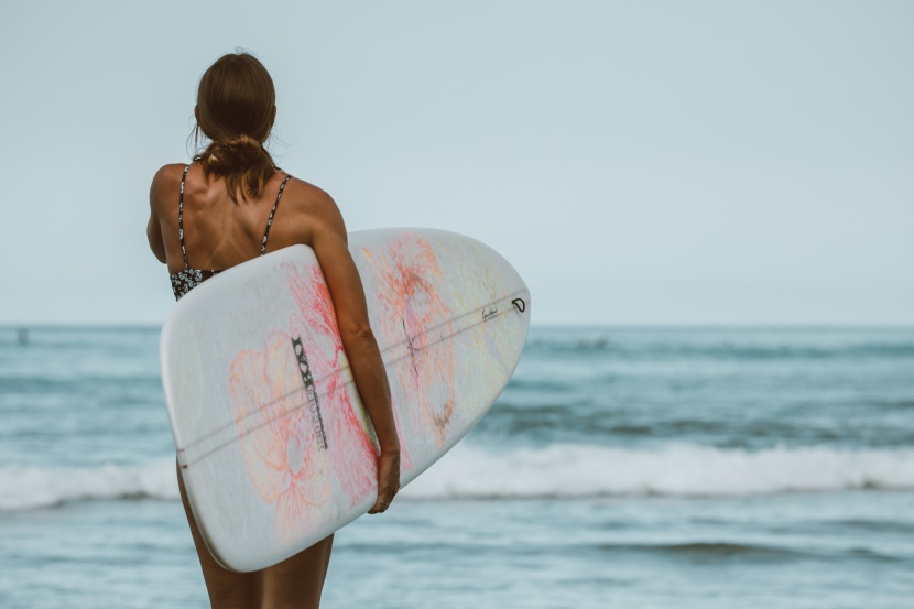 海邊抱着沖浪闆的女子圖片