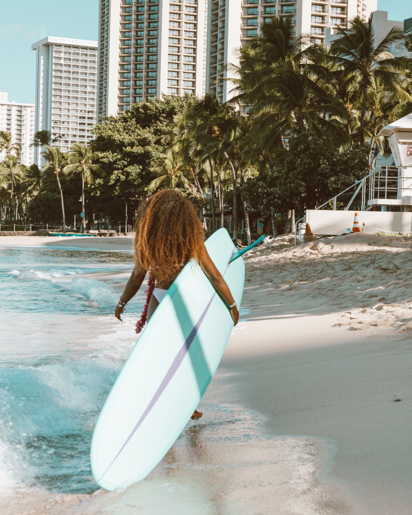 海邊抱着沖浪闆的女子圖片