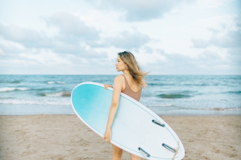 海邊抱着沖浪闆的女子圖片