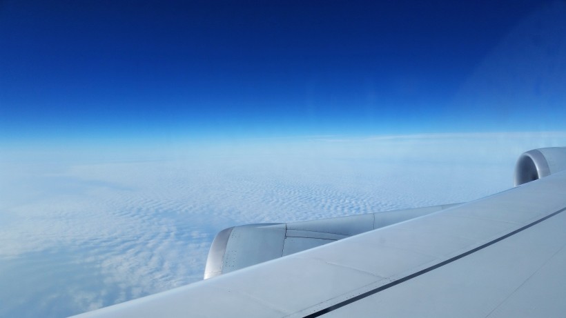 高空雲層上的飛機機翼圖片